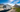 White RV parked by scenic mountains and tranquil lakeside, ideal for road trips, outdoor travel, and adventure vacations.